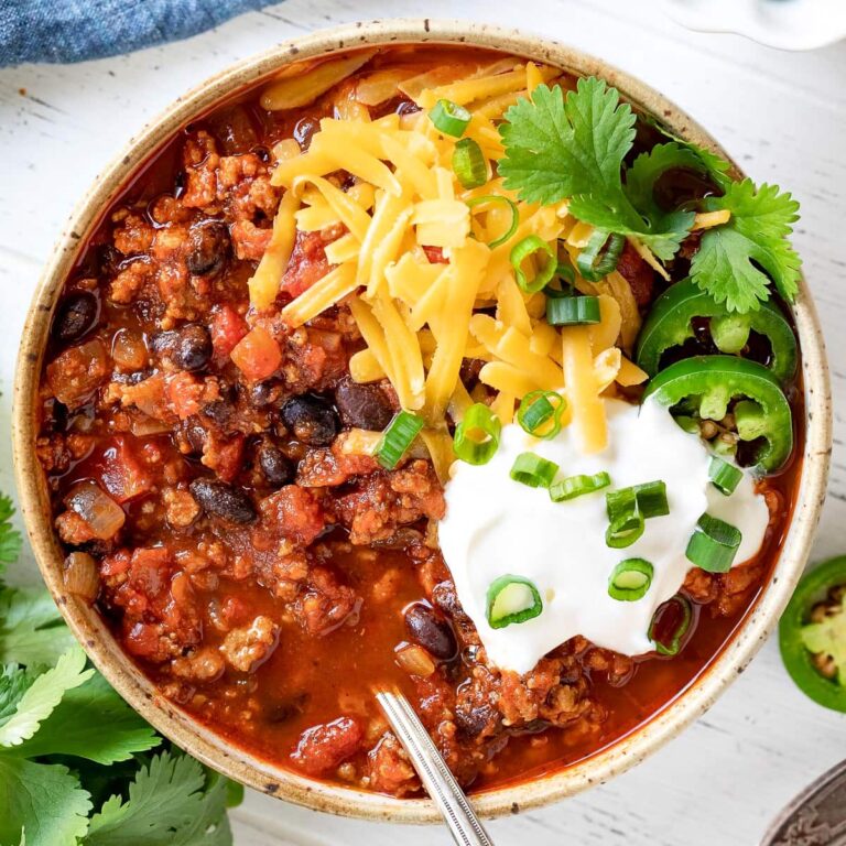 a bowl of turkey chili with cheese and sour cream as toppings